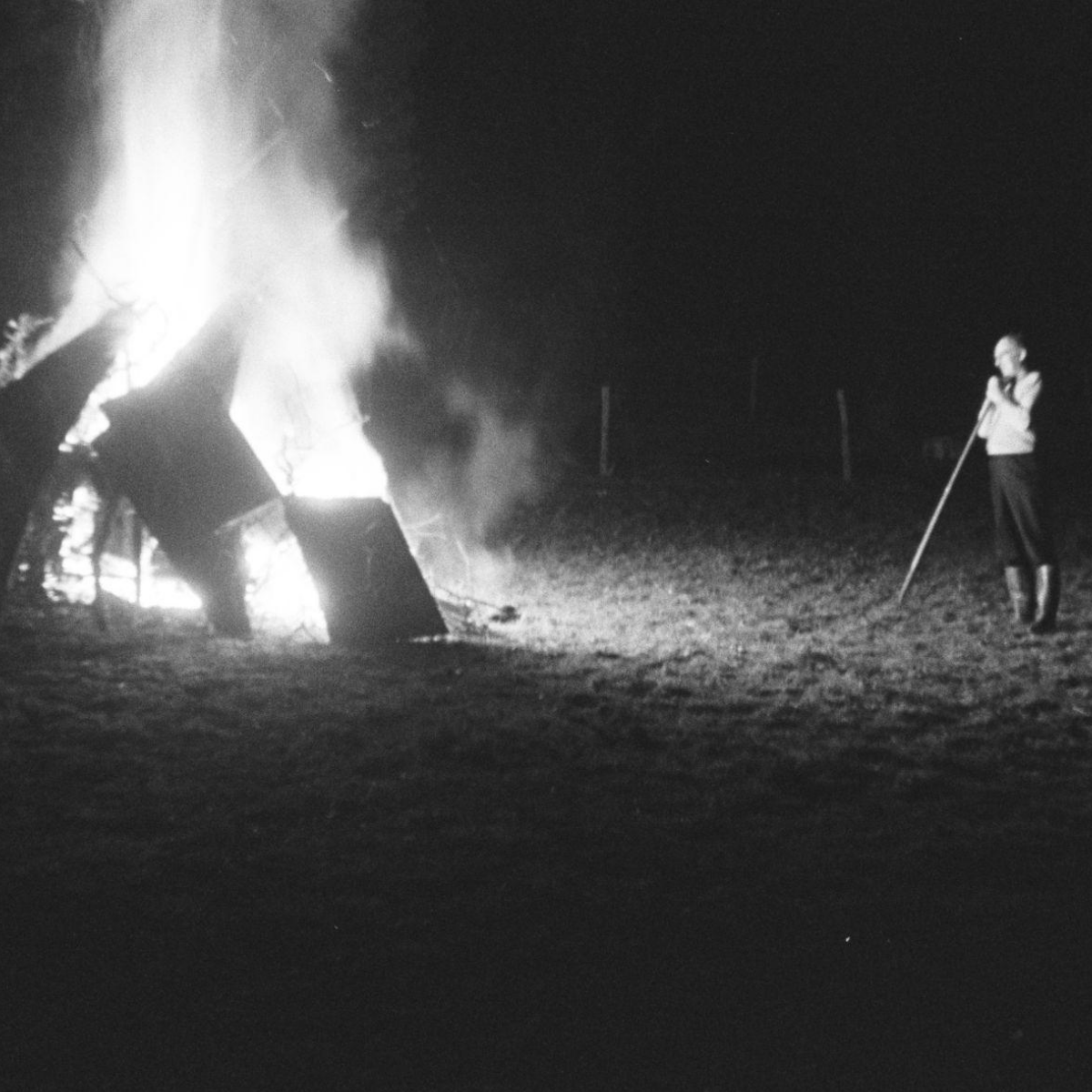 Photo of a man watching a bonfire.